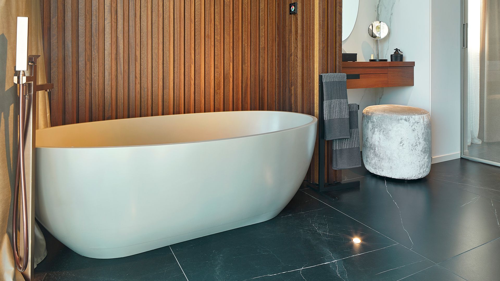 Baño con bañera exenta, paredes de madera, suelo gris, taburete, tocador con espejo, ducha independiente 