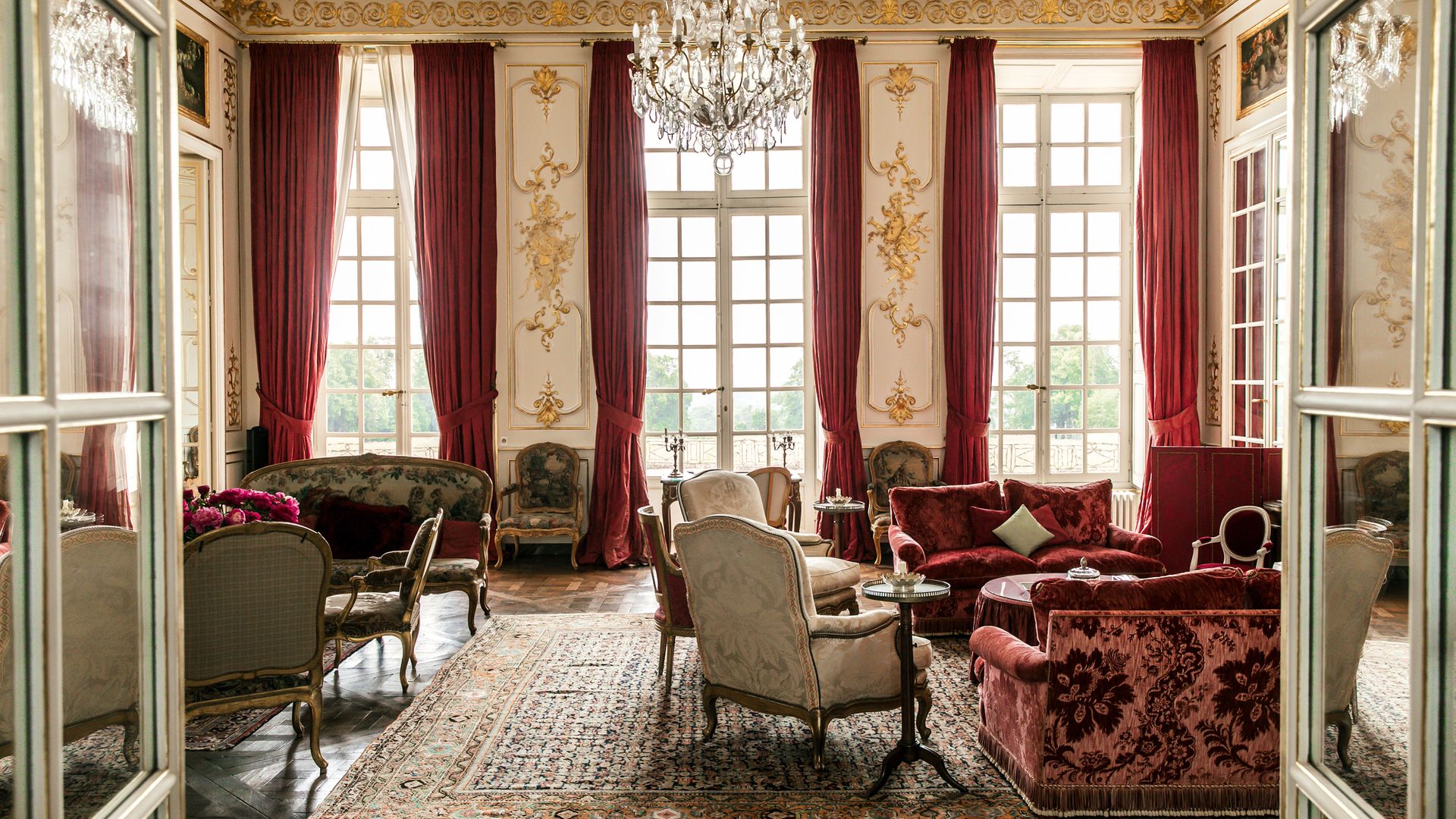 Una vista general y dos rincones del gran salón del castillo, revestido con "boiseries" blancas y doradas que realzan la elegancia de sus muebles del siglo XVIII