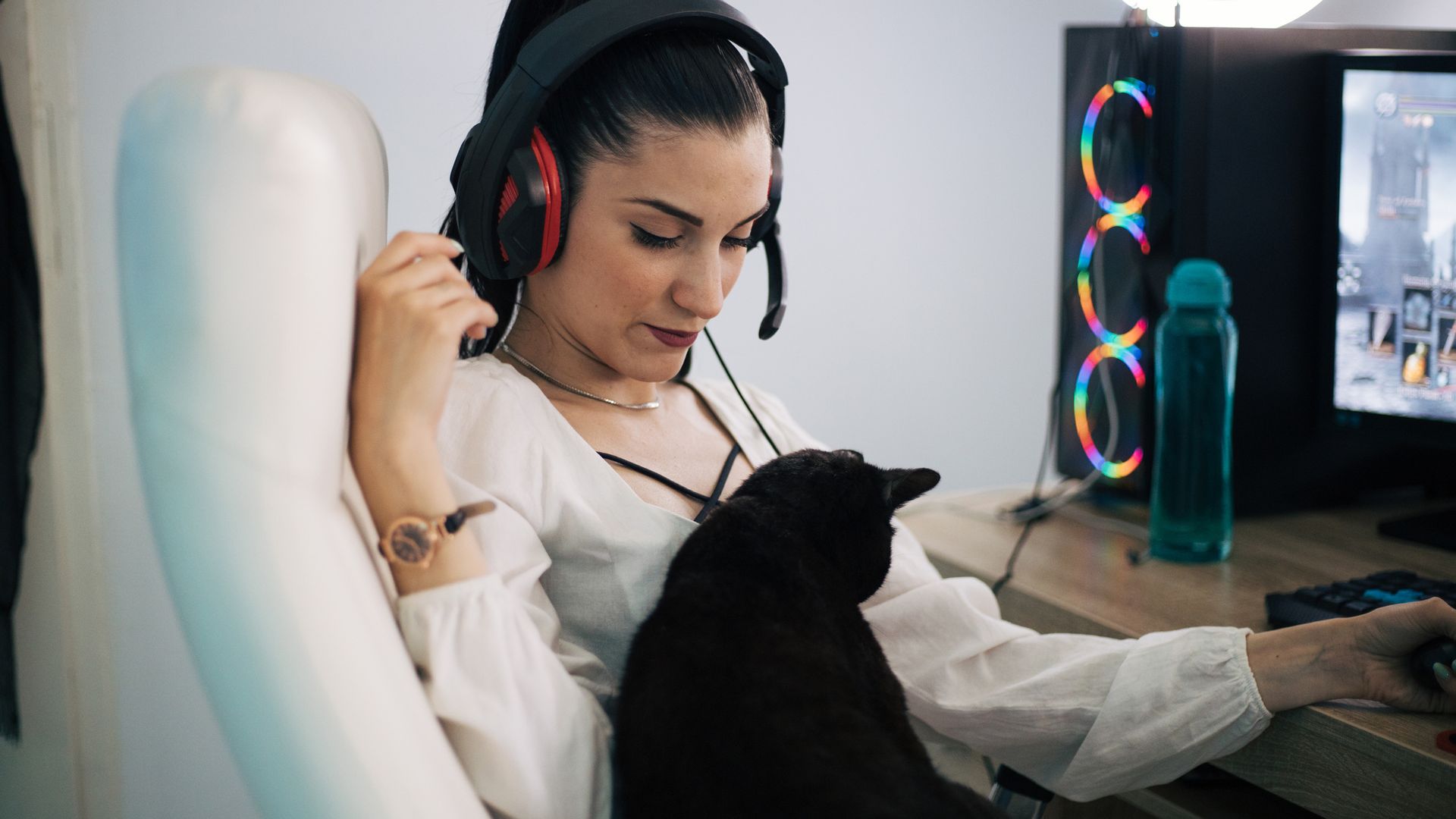 Una chica jugando al ordenador con su gato