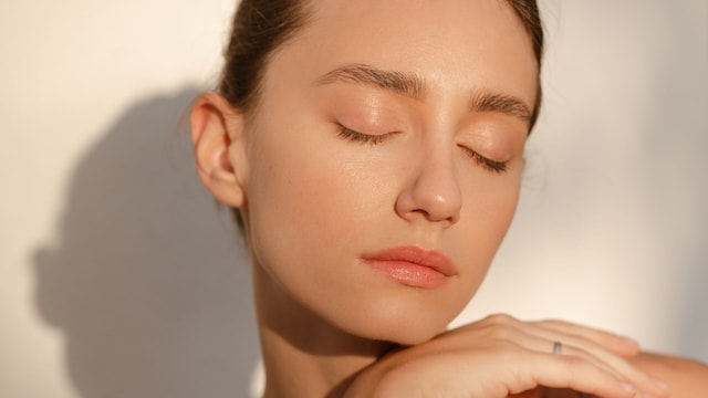 Mujer con la piel del rostro limpia y saludable, con los ojos cerrados en primer plano