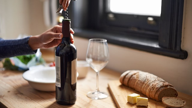 Una mujer abriendo una botella de vino 