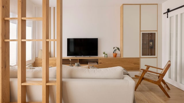 Salón de estilo nórdico con sofá blanco, mueble bajo de madera, alfombra de fibras vegetales, televisión, mueble blanco con vitrina