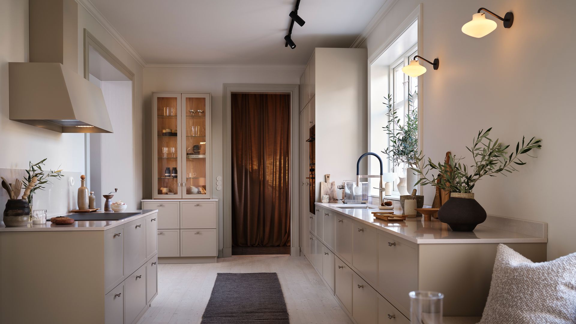 Cocina en beige oscuro con vitrina, alfombra, comedor, focos en el techo, apliques de pared
