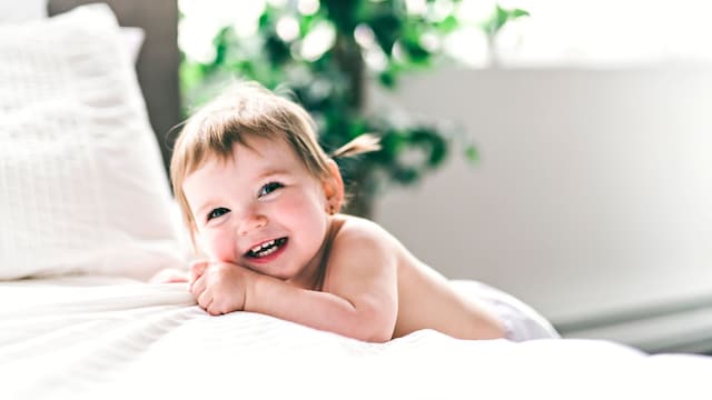 Niña sonríe junto a la cama