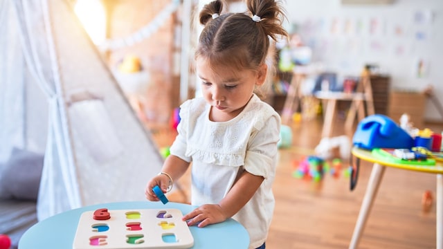 Niña jugando en su habitación llena de juguetes