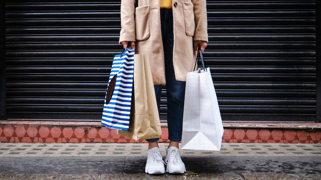 Mujer sujetando bolsas de la compra en la calle en otoño-invierno. 