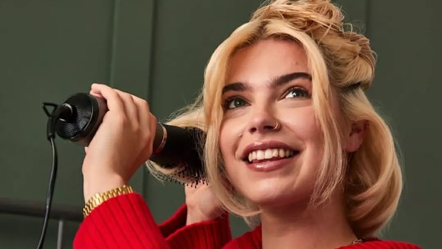 Mujer rubia con pelo corto peinándose con cepillo moldeador de Remington