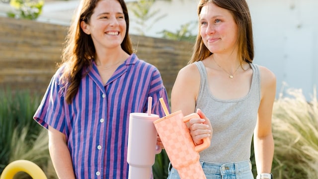 Dos chicas sonriendo en verano con una botella de agua de acero inoxidable en la mano de Simple Modern