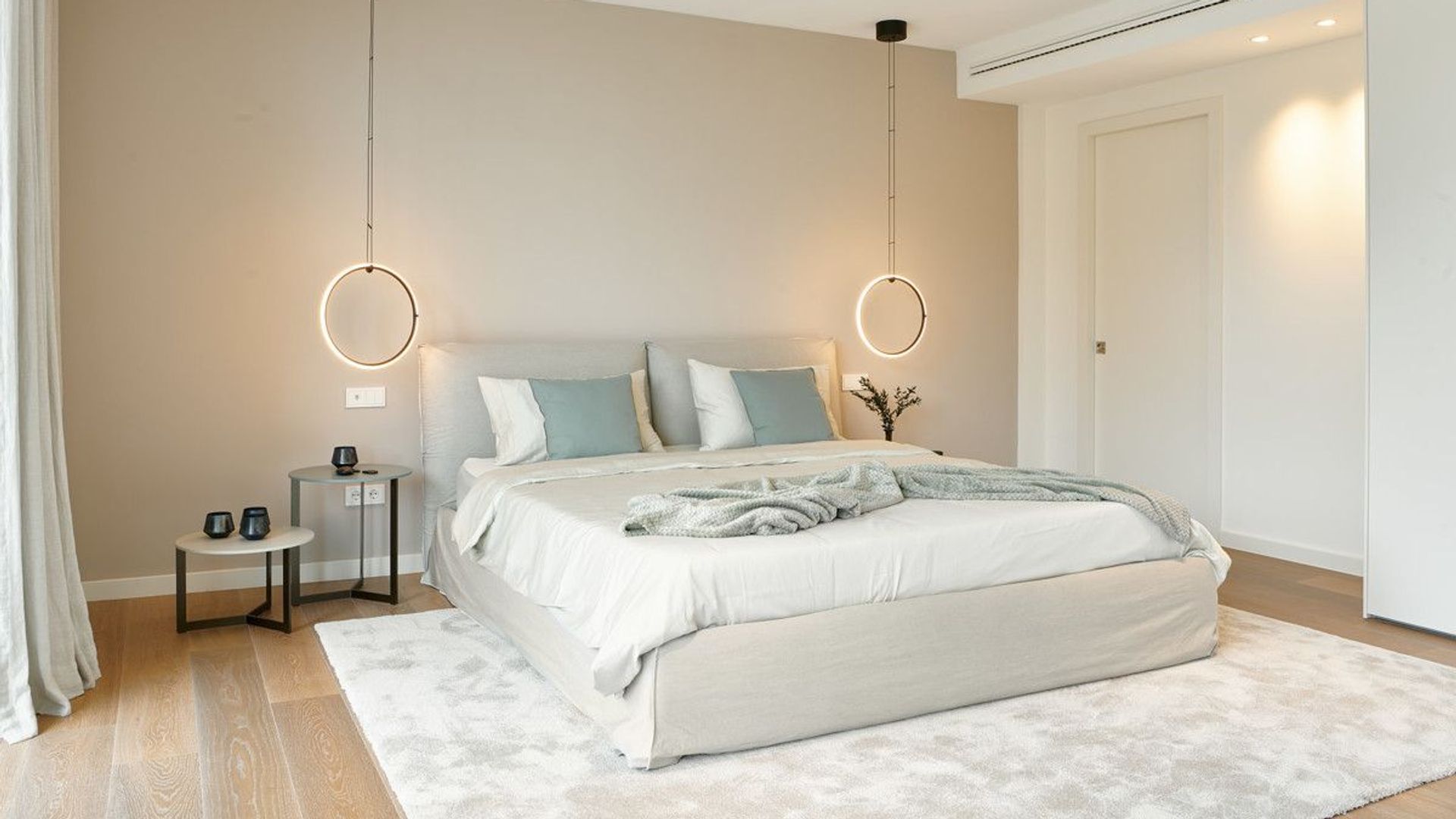 Dormitorio con cama tapizada, cabecero tapizado, colores claros, lámparas de techo a ambos lados de la cama, alfombra 
