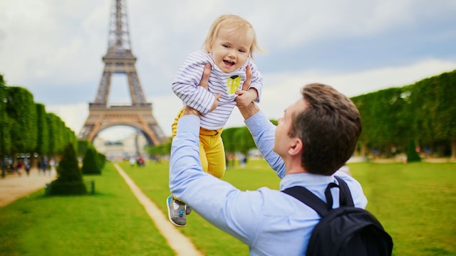 Padre alza a su bebé frente a la torre Eiffel de París