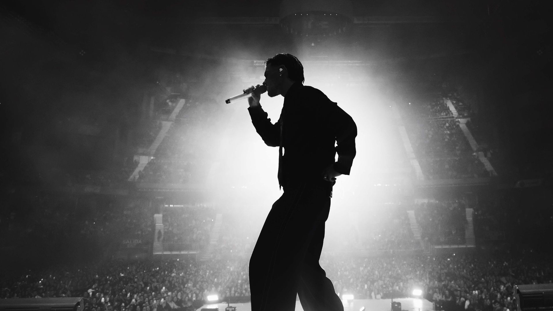 Abraham Mateo en el escenario con micrófono, frente a una audiencia en concierto.
