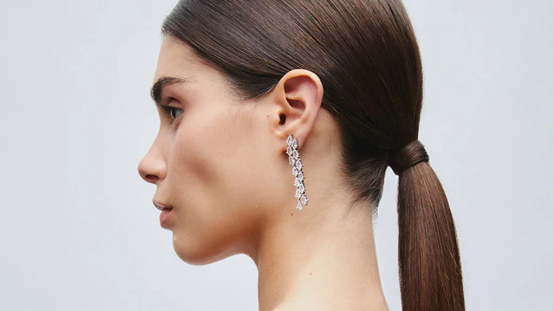 Mujer joven con coleta baja pulida y pendientes largos de brillantes de VIDAL & VIDAL