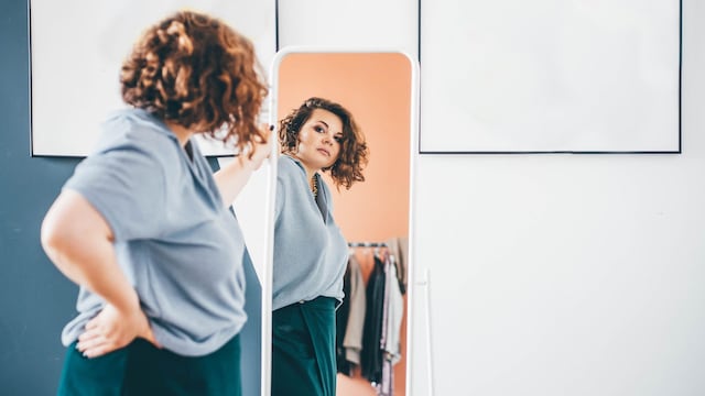 mujer con sobrepeso mirándose en el espejo
