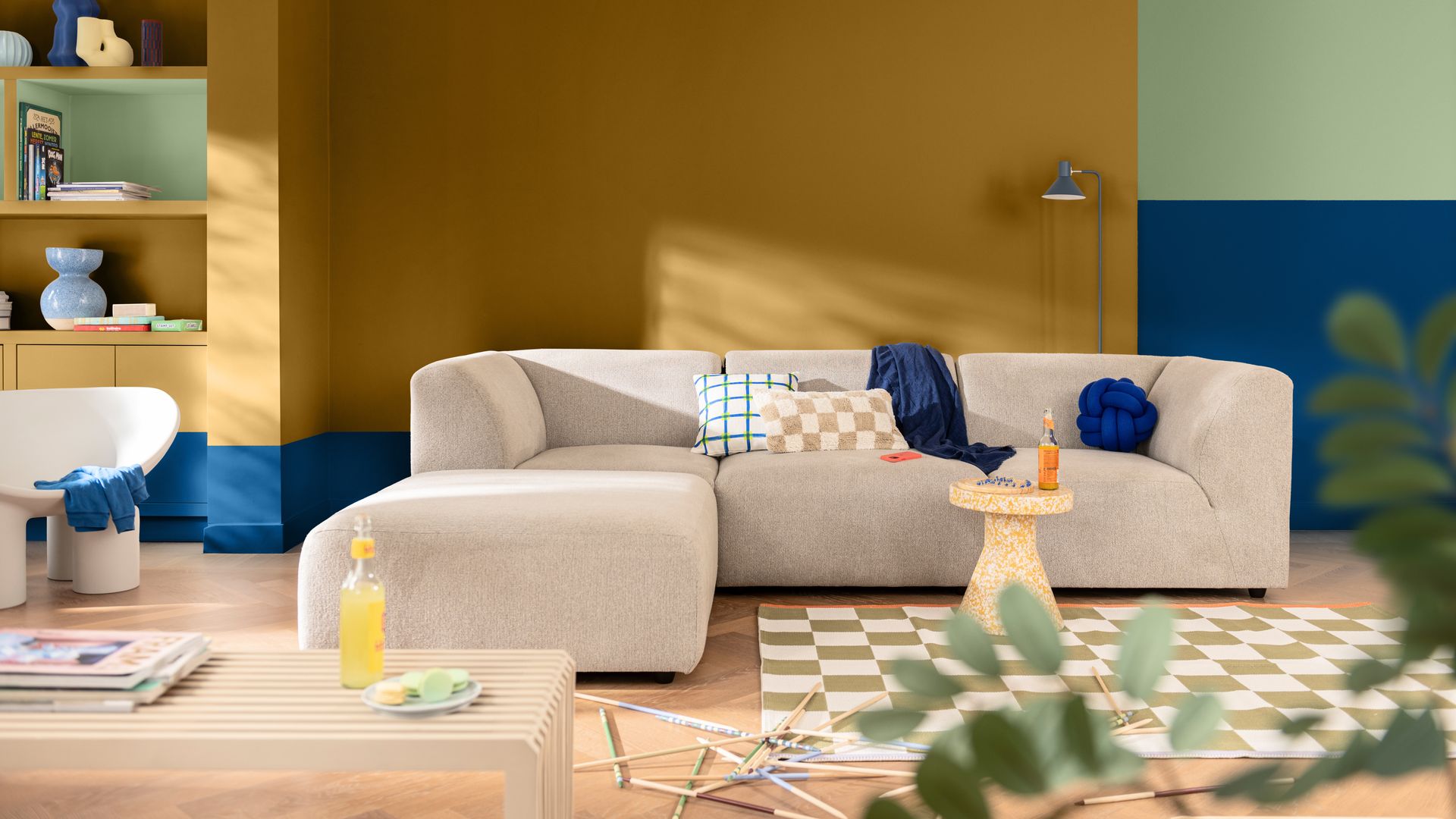 Salón con sofá beige, pared de color mostaza y zócalo azul cobalto con pared verde claro