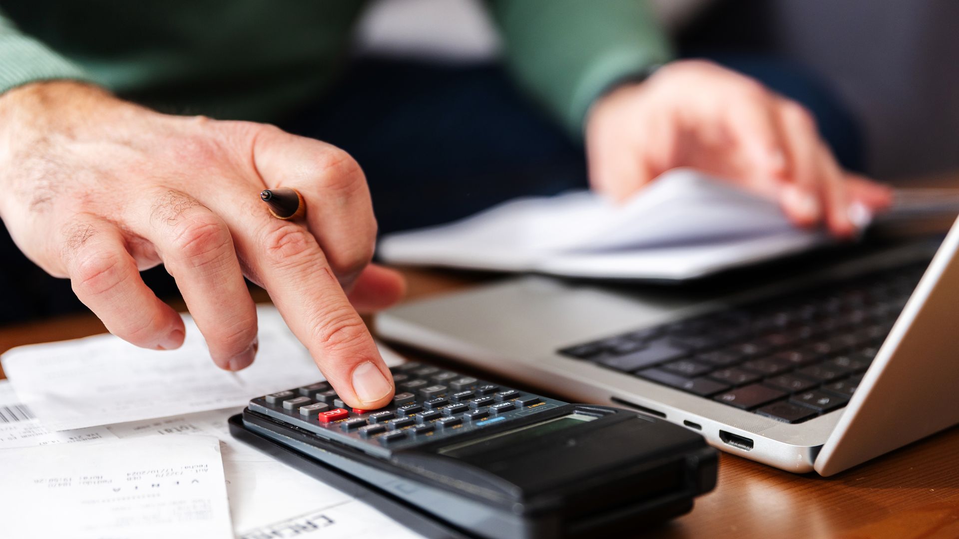 Hombre haciendo cuentas con calculadora y ordenador