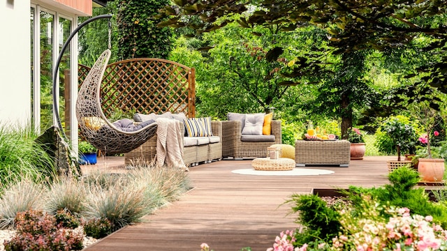 Una terraza con mobiliario de jardín rodeado de vegetación