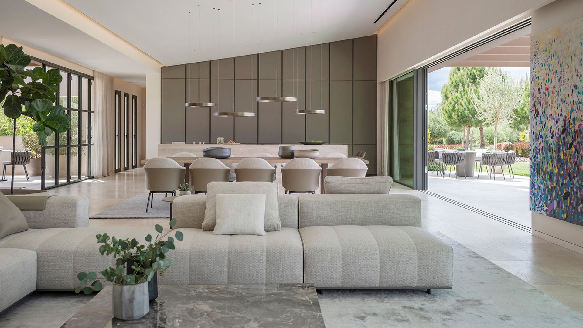 Espacio único con cocina, salón y comedor con armarios hasta el techo, sofás blancos, mesa de comedor y sillas a juego