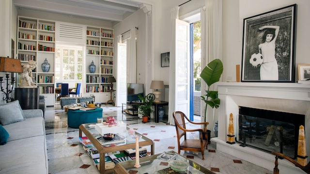 Salón con chimenea con foto en blanco y negro, librerías hasta el techo, suelo cerámico, sofá blanco, mesas de centro con sobre de cristal