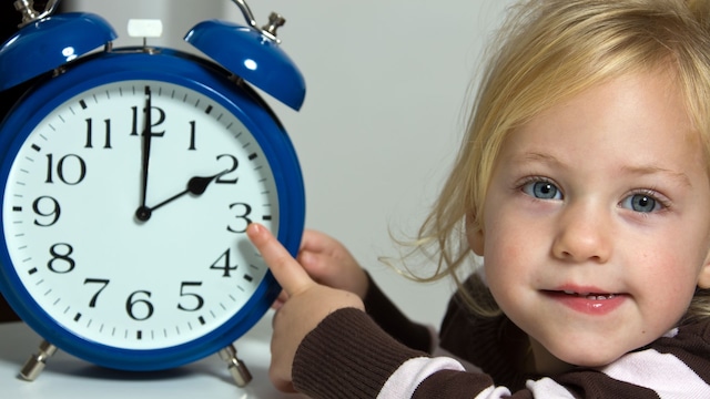 Niña señalando un reloj