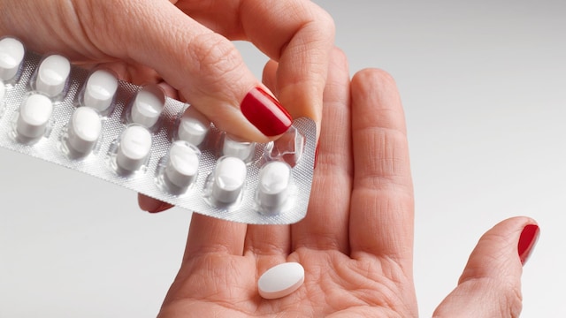 manos de mujer cogiendo una pastilla de un blister