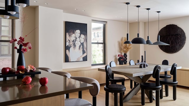 Comedor y cocina, con fotografía en blanco y negro, mesa de madera, sillas negras, lámparas de techo negra, isla con taburetes altos