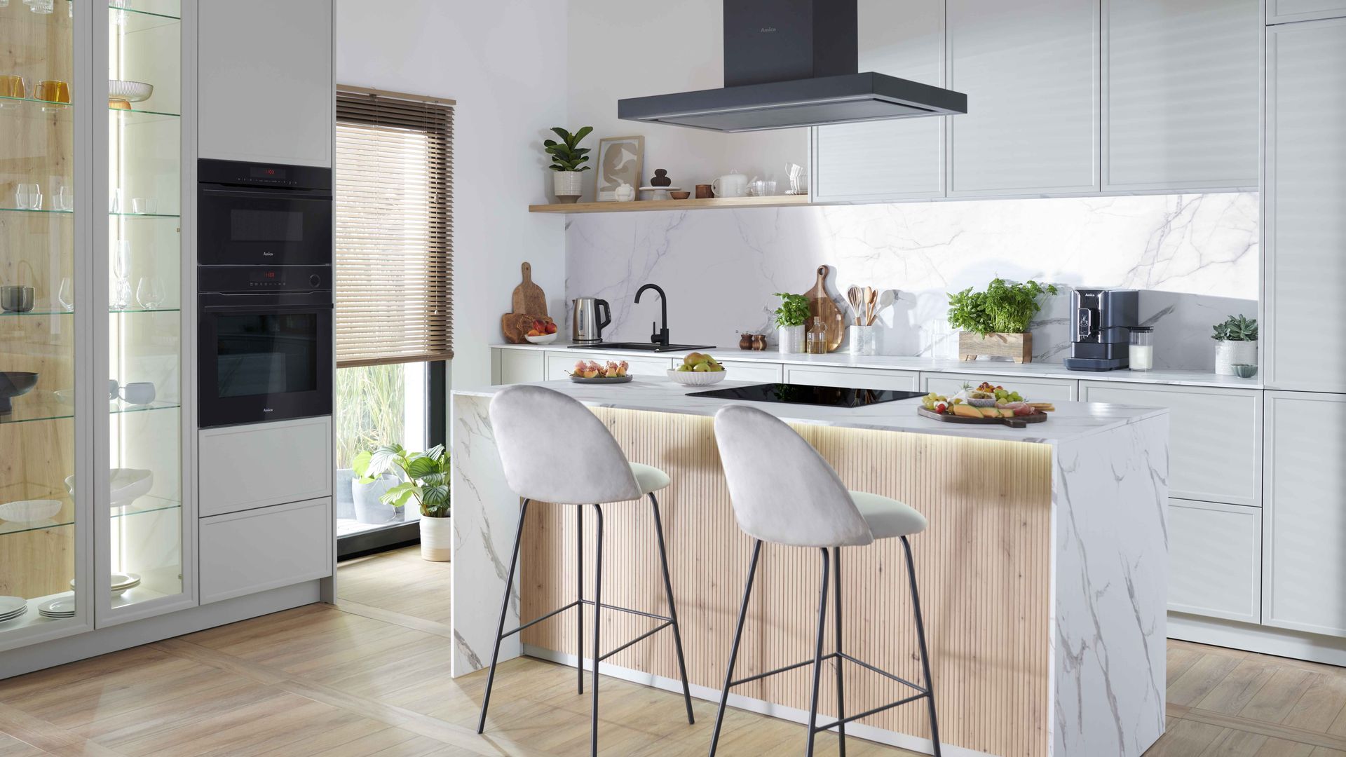 Cocina con isla, muebles blancos, campana de techo, suelo de madera, vitrina, electrodomésticos en columna