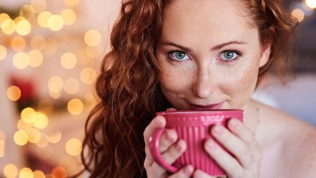 Mujer pelirroja bebiendo una taza de té en Navidad