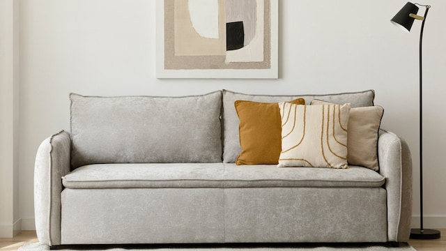 Sofá cama en gris en un salón en tonos blancos y beiges.