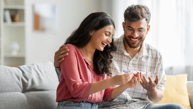 Pareja sonríe al ver el resultado de un test de embarazo