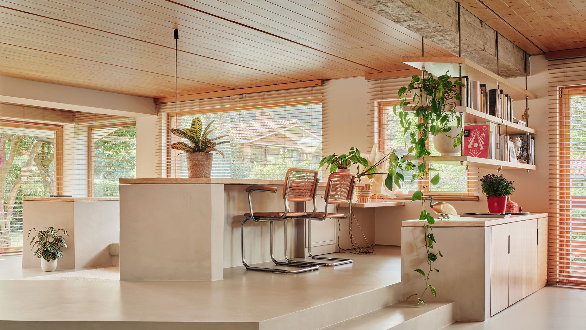 Despacho abierto al salón y al comedor con estanterías de madera flotantes y aparador 