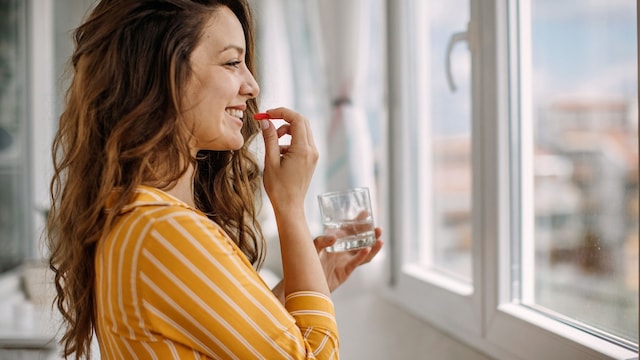 mujer tomando suplementos en casa