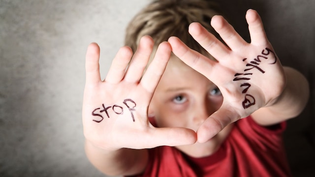 Niño con mensaje pintado en las manos de STOP Bullying