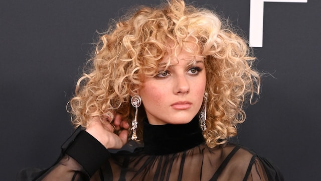 Grace Bowers con blusa negra transparente y pelo rizado en los Premios Grammy 2025