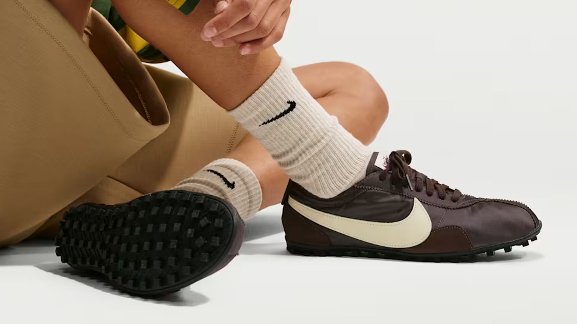 Modelo con ropa de Nike y zapatillas Moon Shoes OG sentada en el suelo