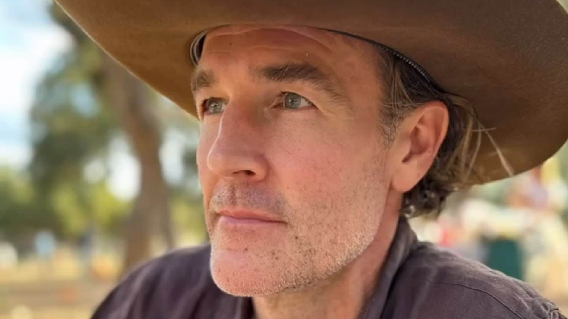 Plano medio de James Van Der Beek con camisa y sombrero marrón