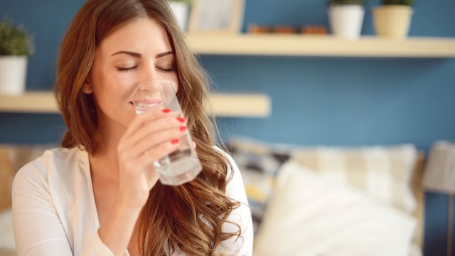 Mujer tomando una medicación sosteniendo un vaso de agua