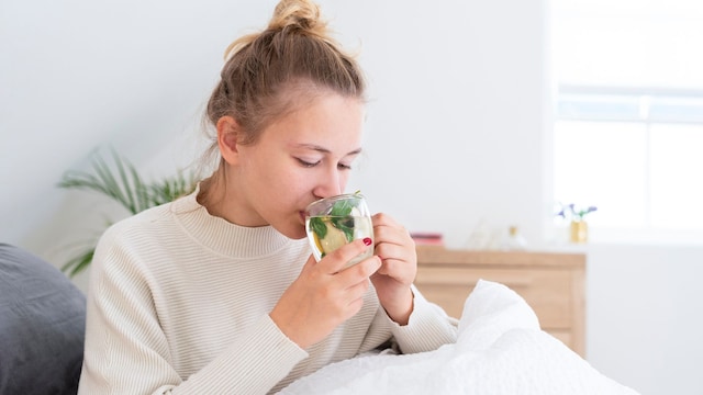 mujer en la cama tomando una infusión