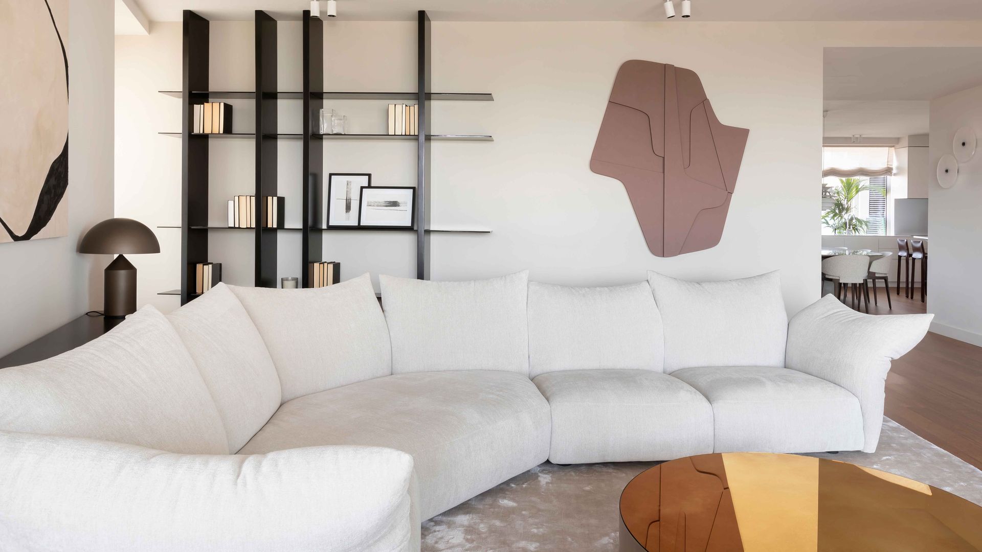 Salón con sofá blanco, estantería negra, cuadros, alfombra