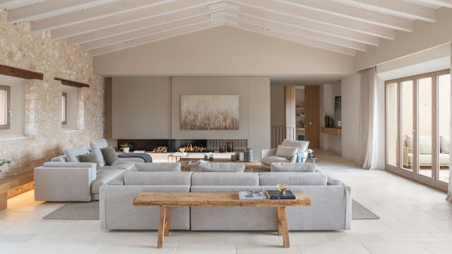 Salón con paredes de piedra, techo con vigas de madera, gran ventanal con salida al jardín, sofás de color gris, banco de madera, chismean 