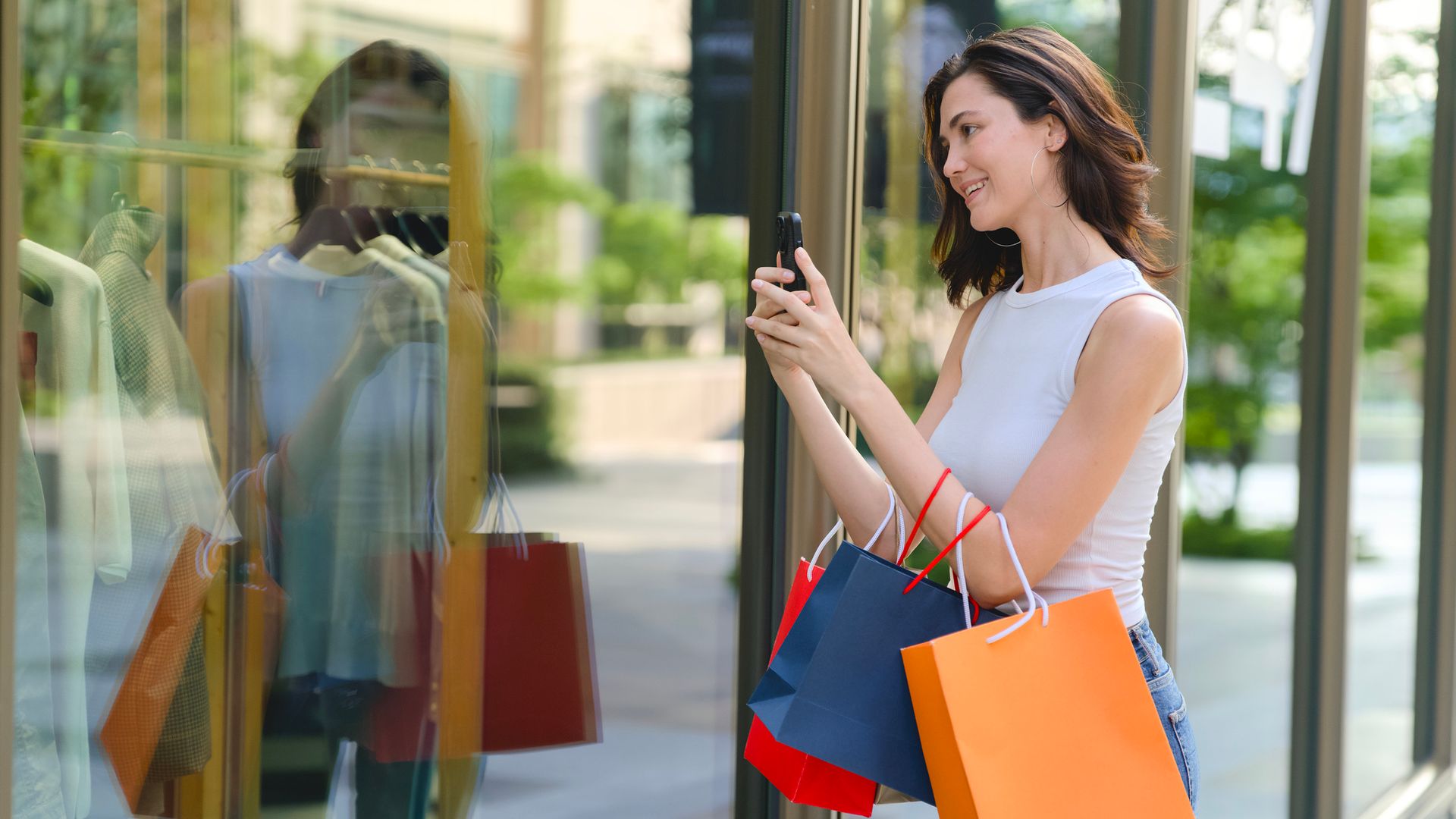 Mujer tomando una fotografía de un escaparate con ropa de verano.