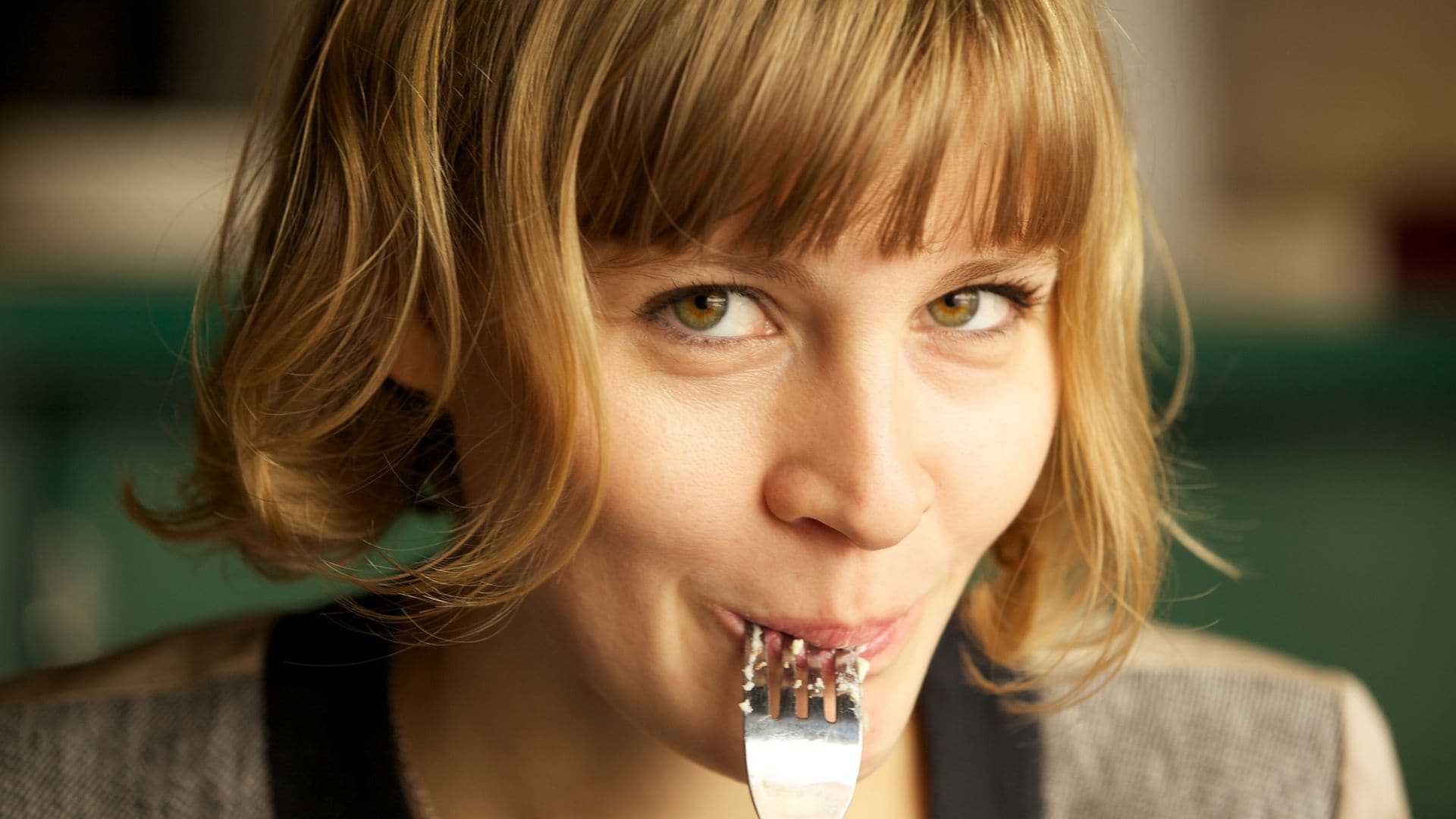 Mujer comiendo con un tenedor en la boca 