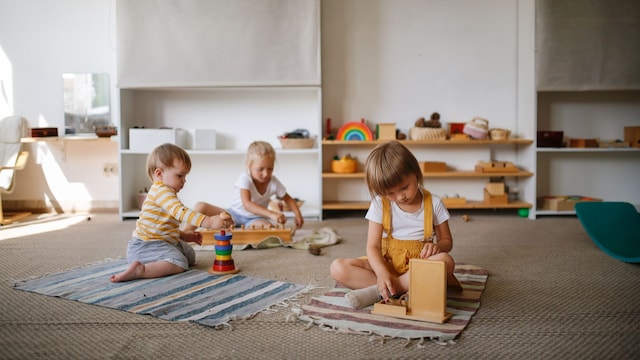 Niños jugando en el suelo con juguetes de madera en la guardería