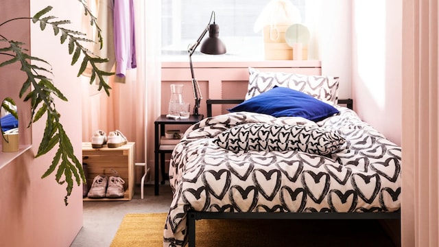 Habitación de piso pequeño en rosa con cama negra de IKEA