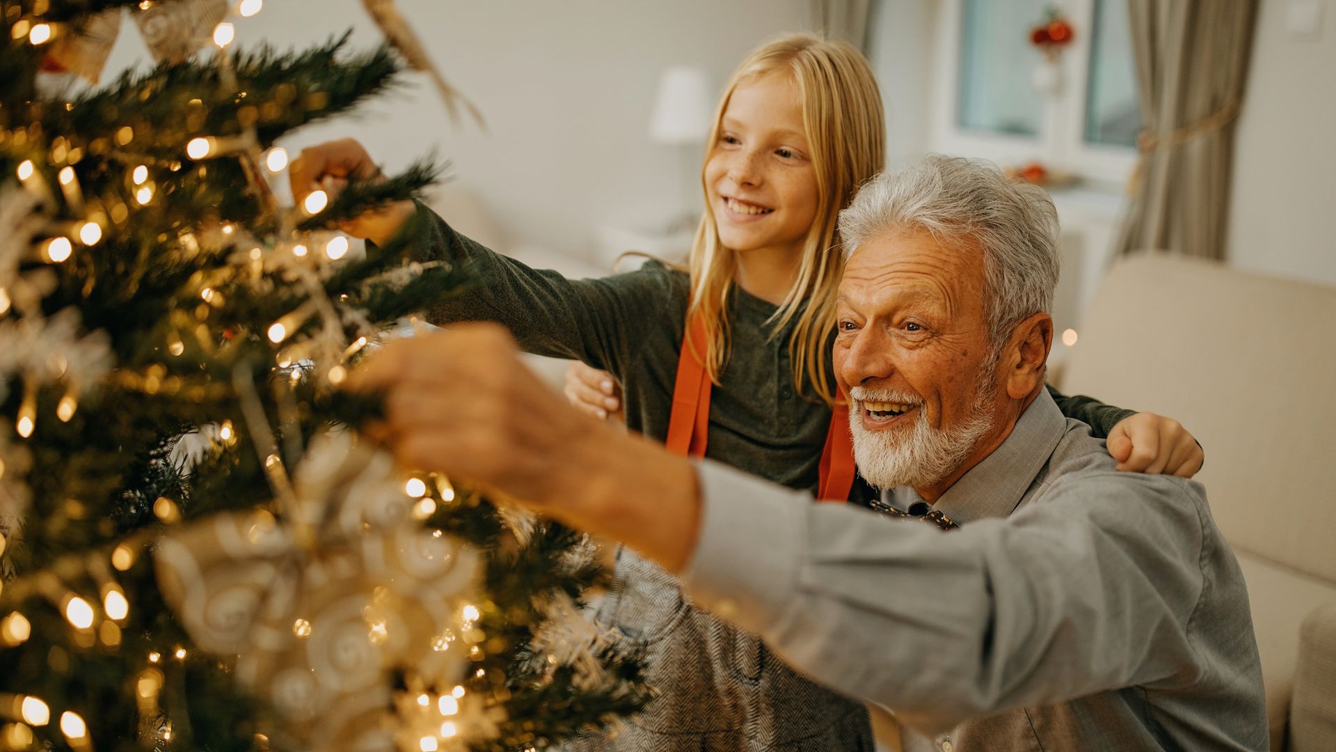 abuelo y nieta decorando el árbol de Navidad