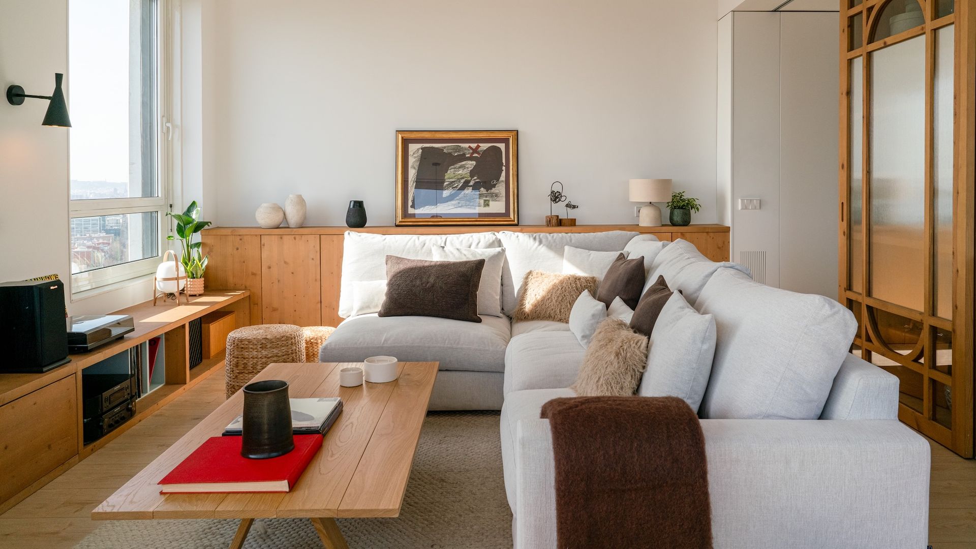 Salón con sofá blanco en L y muebles de madera.  