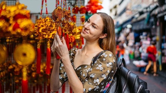 Beautiful young woman shopping for Chinese New Year decorations in Chinatown in Bangkok in Thailand.