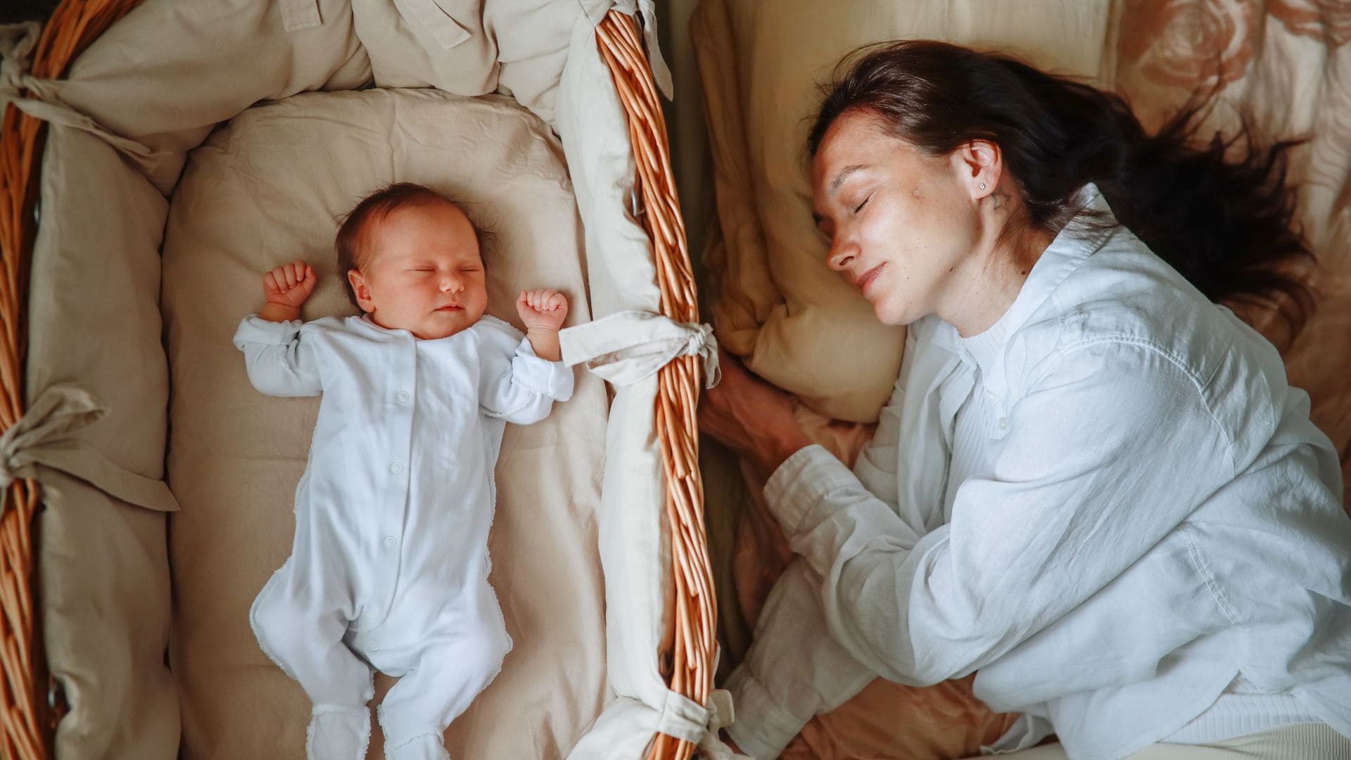 Madre duerme, feliz, junto a su bebé recién nacido