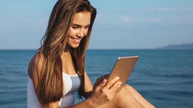Una chica con una tablet junto al mar