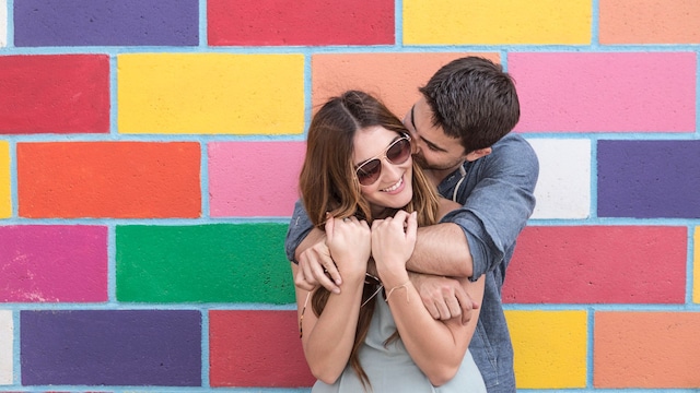pareja feliz junto a una pared muy colorida
