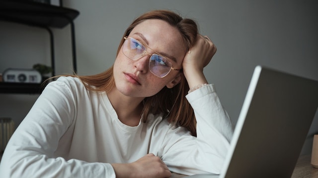 mujer con gafas de ver cansada frente al ordenador